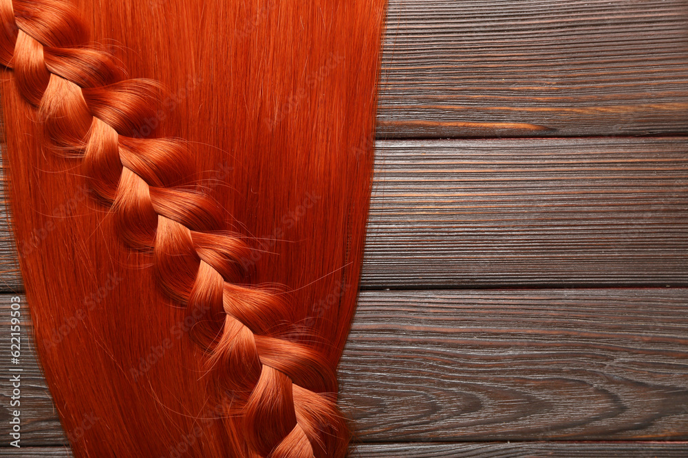 Ginger hair with braid on wooden background, closeup