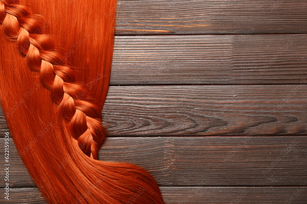 Ginger hair with braid on wooden background, closeup