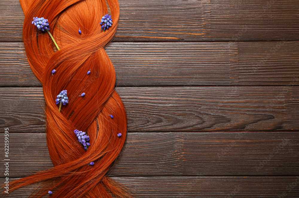 Beautiful ginger hair with Muscari flowers on wooden background, closeup