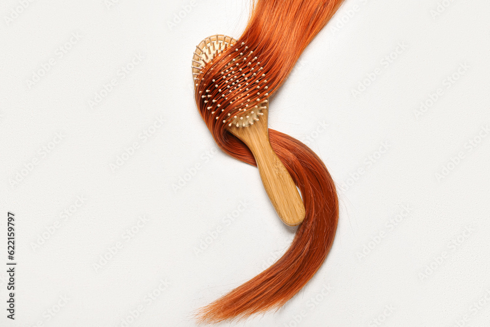 Ginger hair strand with brush on light background