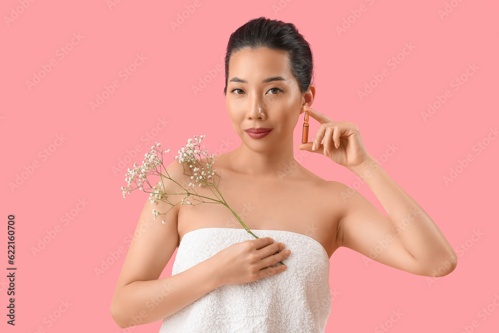 Beautiful Asian woman with ampule and flowers on pink background. Skin care concept