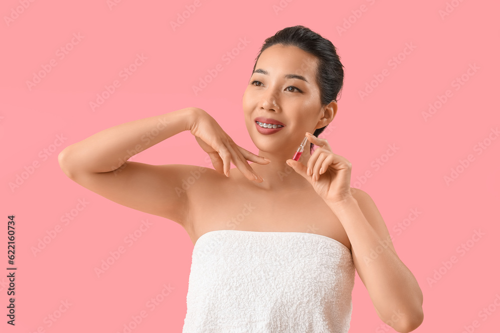 Beautiful Asian woman with ampule on pink background. Skin care concept