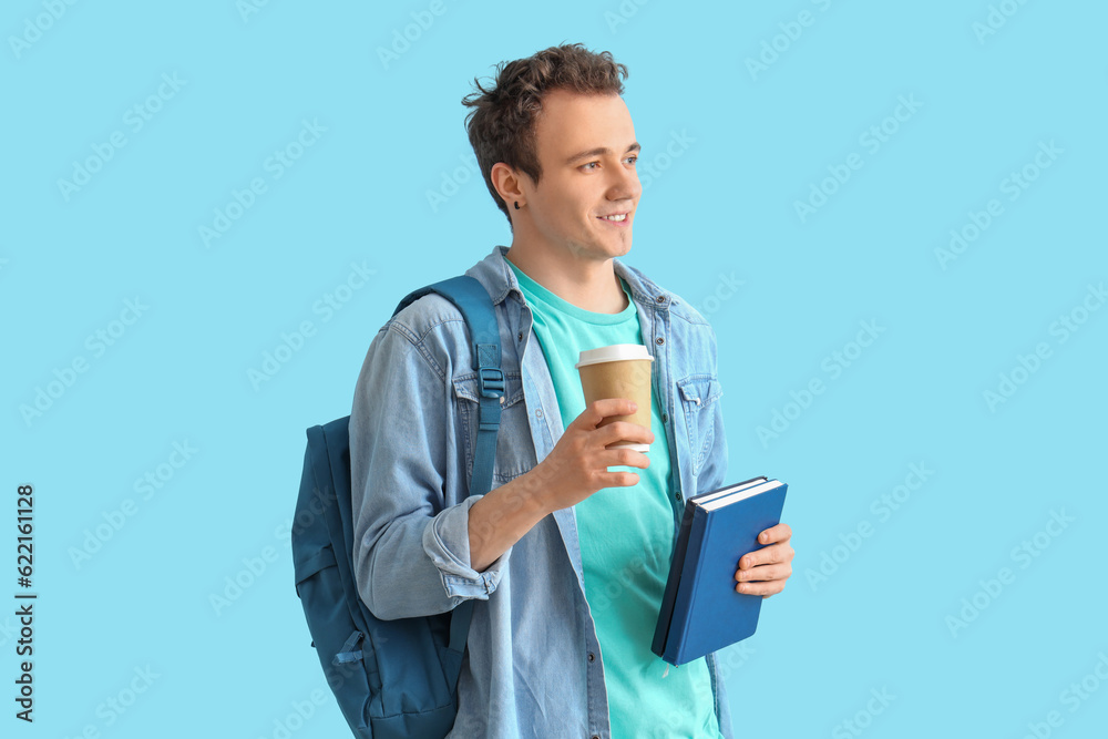 Male student with backpack, books and cup of coffee on blue background