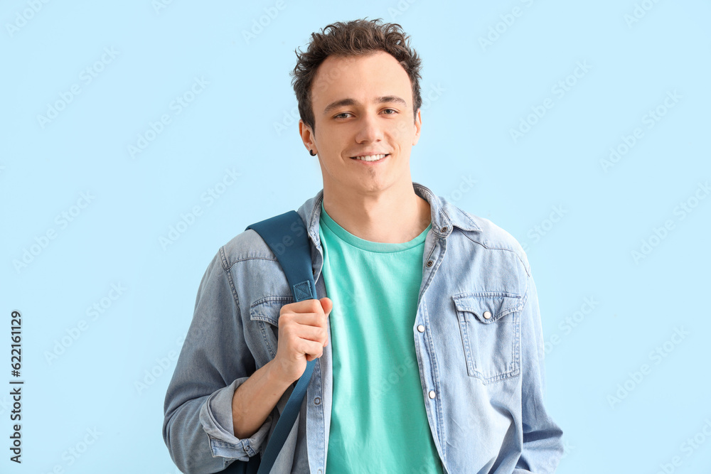 Male student with backpack on blue background