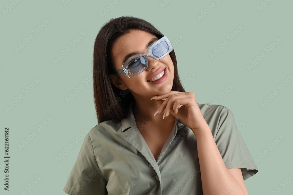 Beautiful young woman wearing stylish  sunglasses on color background