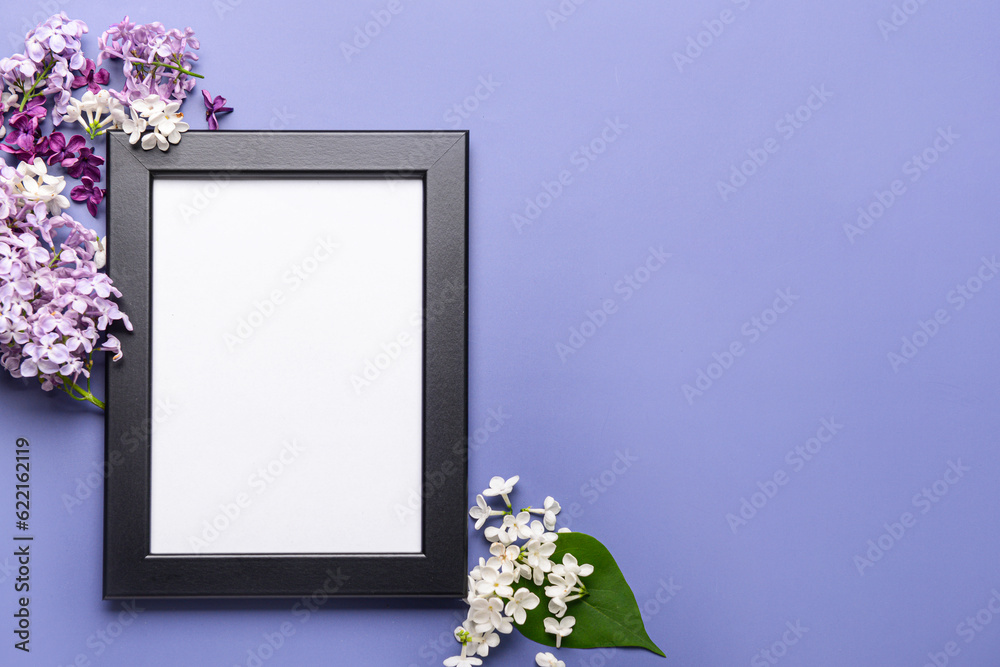 Composition with beautiful lilac flowers and blank frame on blue background