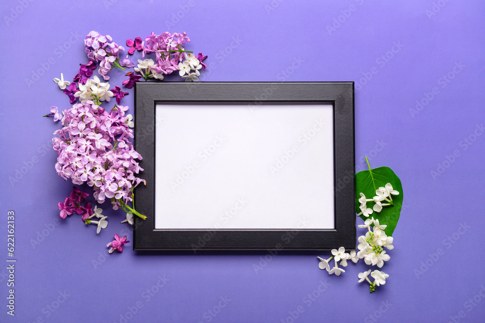 Composition with beautiful lilac flowers and blank frame on blue background