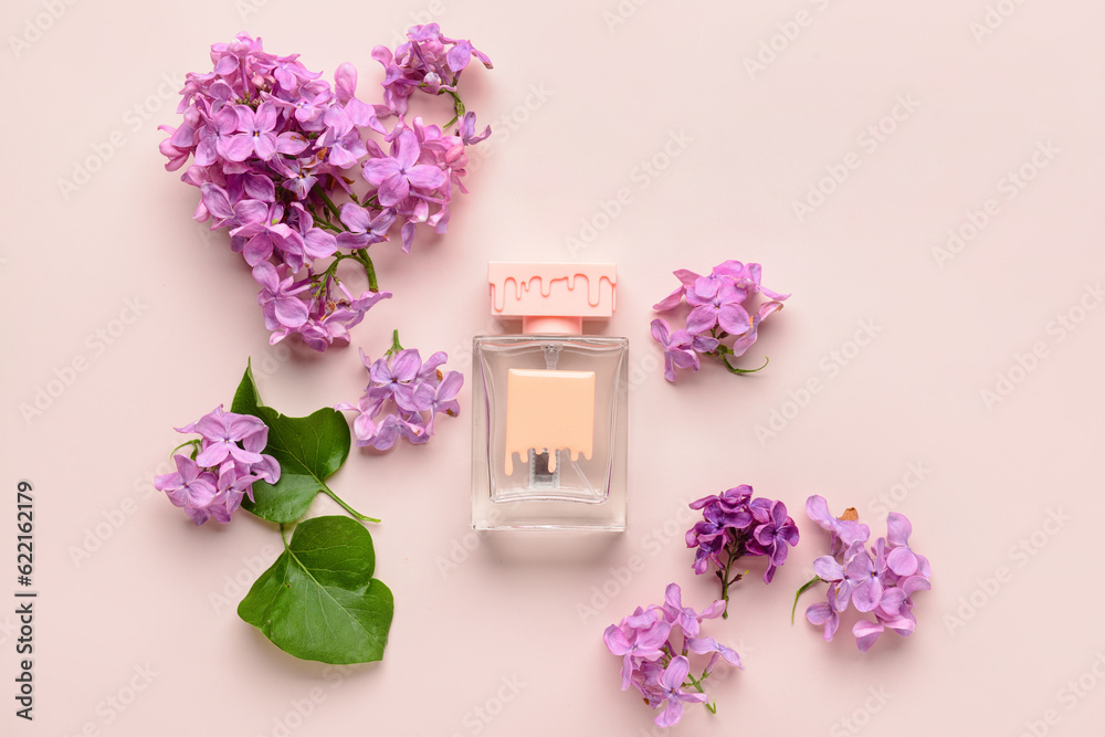 Beautiful lilac flowers and bottle of perfume on beige background