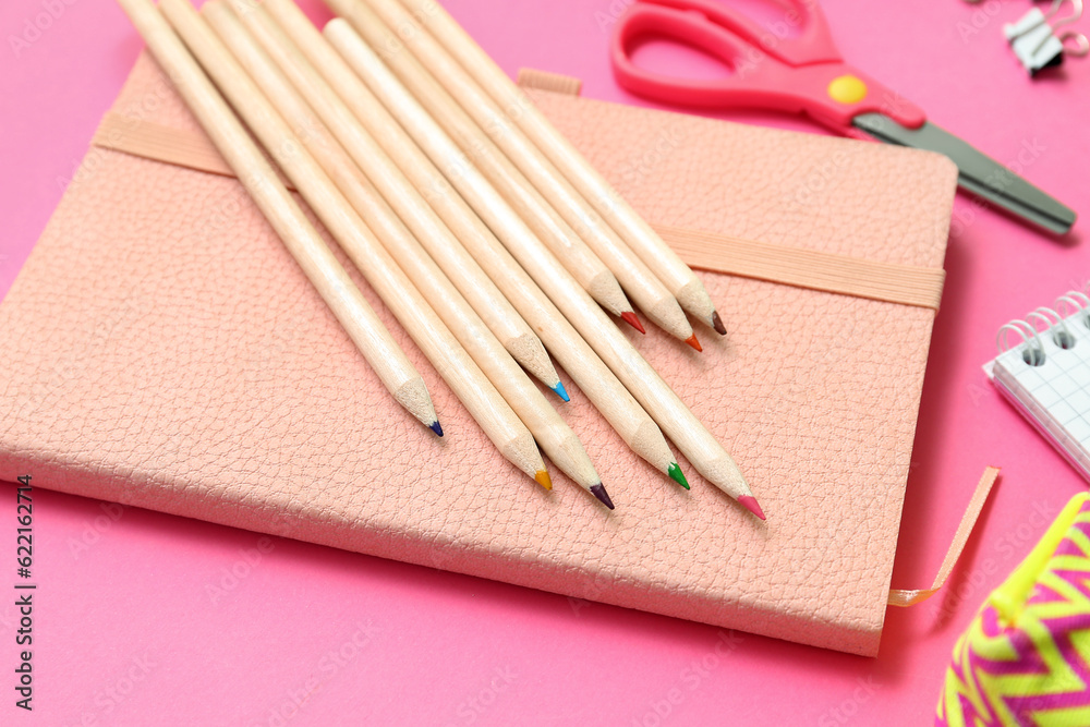 Notebook and pencils on pink background