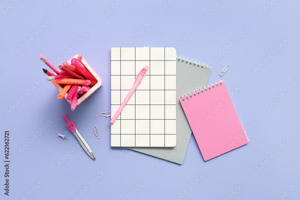 Notebooks and school stationery on lilac background