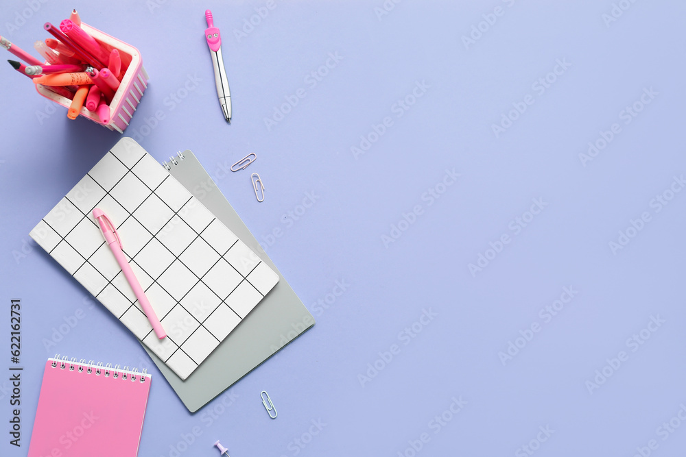 Notebooks and school stationery on lilac background