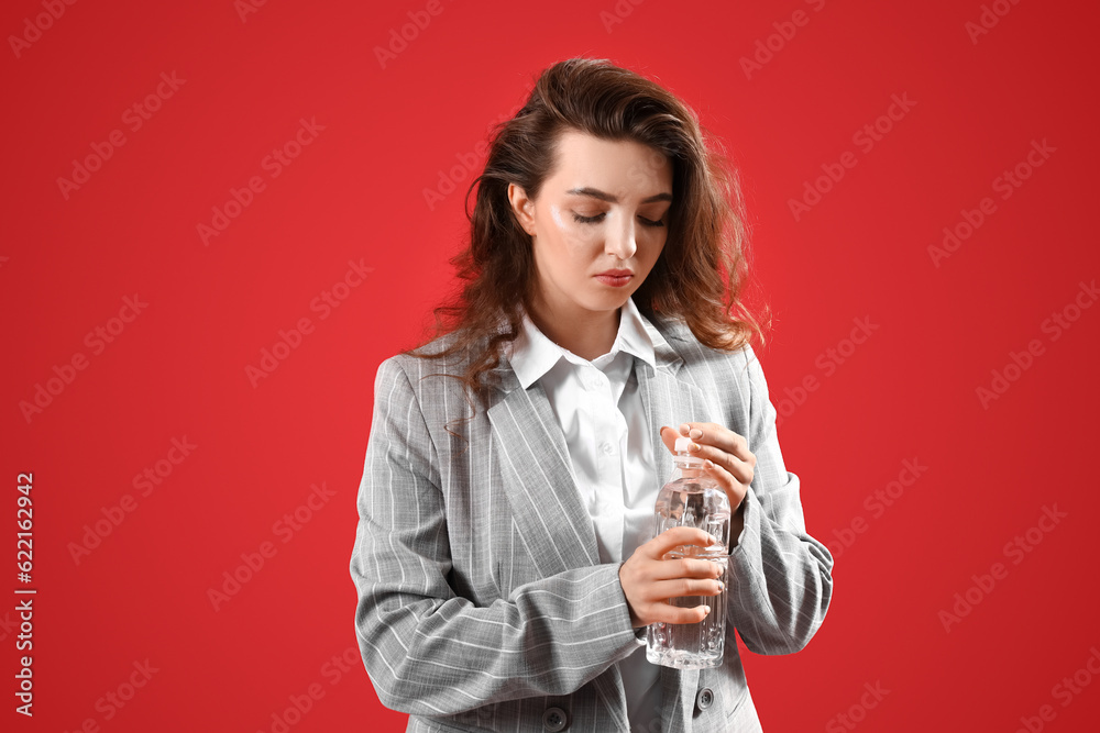 Young woman with bottle of water on red background