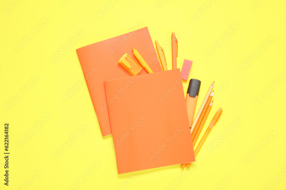 Notebooks with different stationery on yellow background