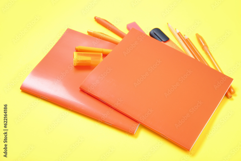 Notebooks with different stationery on yellow background