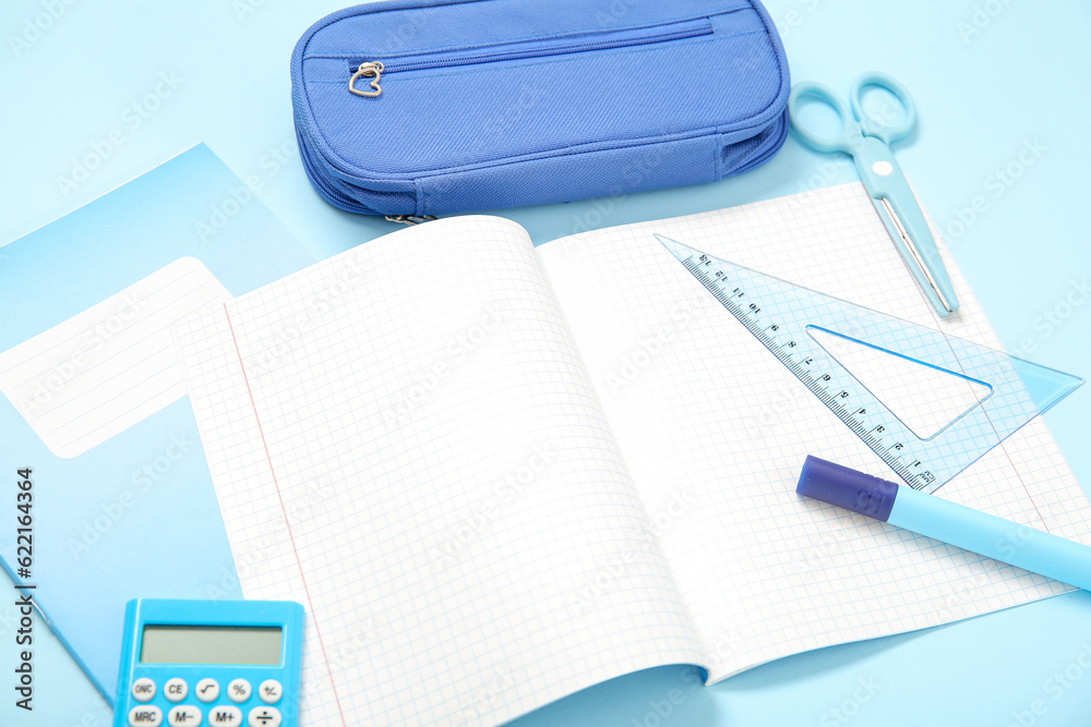 Notebooks with pencil case and different stationery on blue background