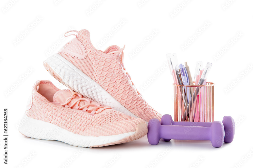 Sneakers with dumbbells and stationery holder isolated on white background