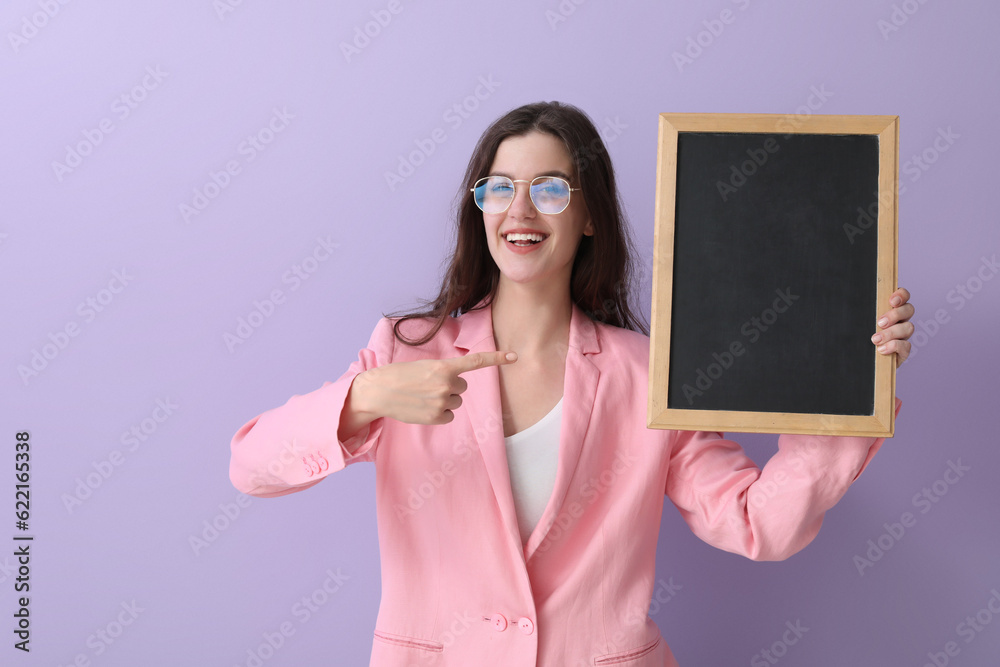 Female teacher pointing at chalkboard on lilac background