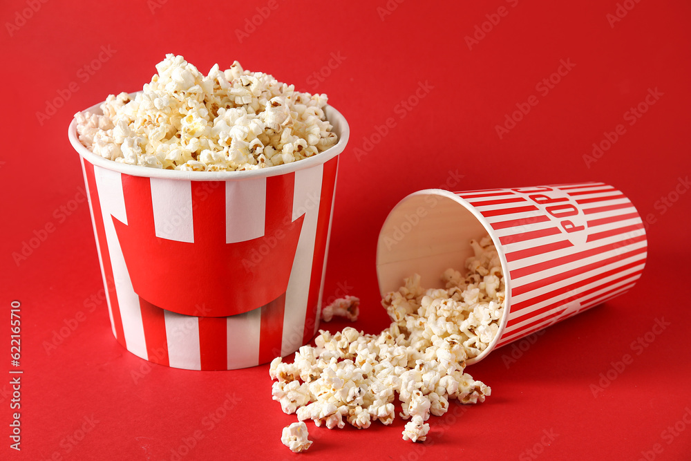 Buckets with tasty popcorn on red background