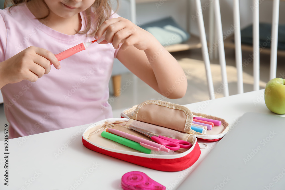 Little girl with pencil case at table, closeup