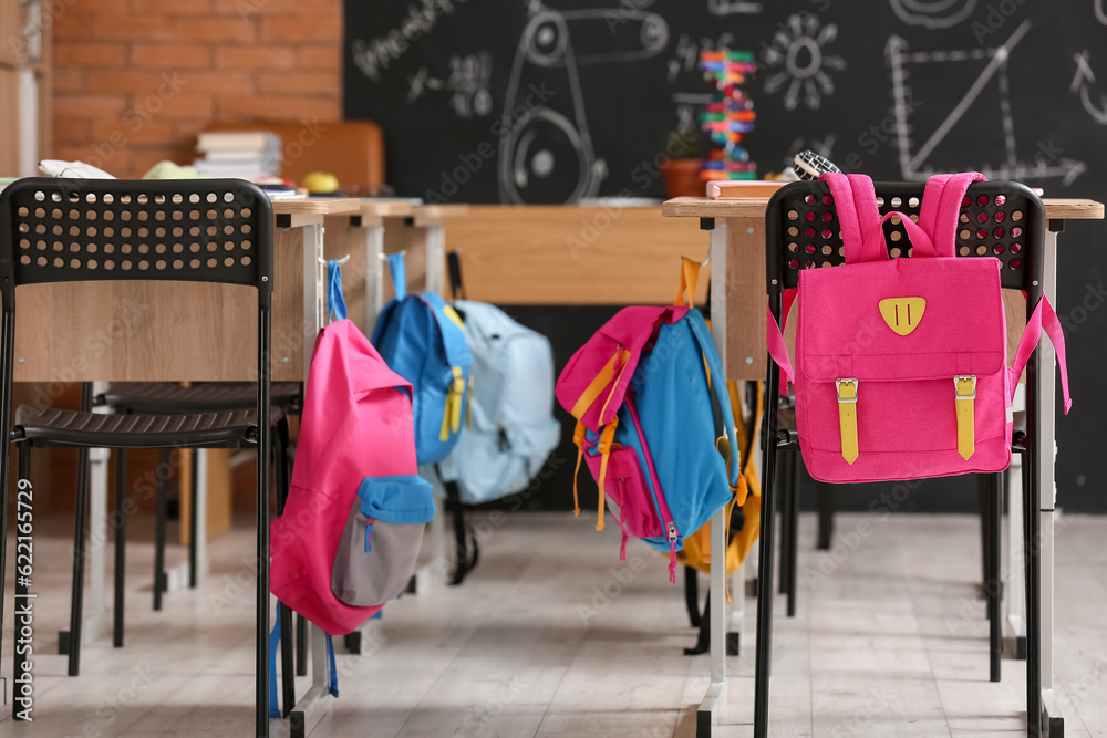 Chairs with desks and backpacks in classroom