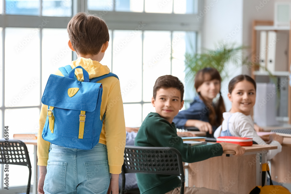 Little boy with backpack in classroom, back view