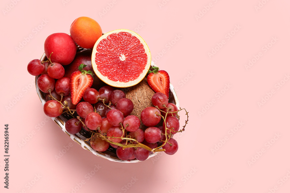 Wicker bowl with different fresh fruits on pink background