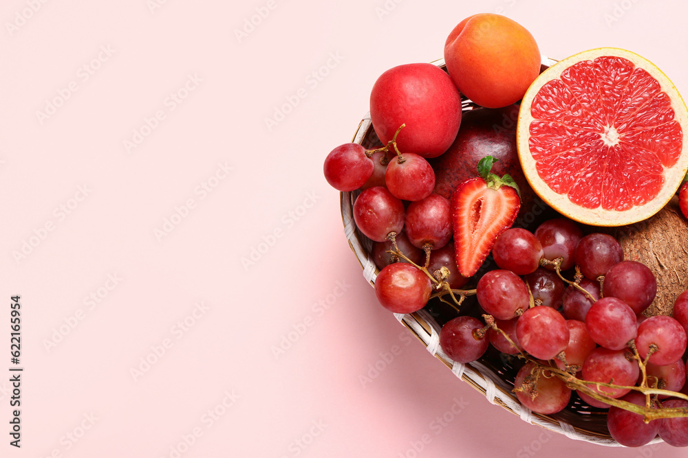 Wicker bowl with different fresh fruits on pink background