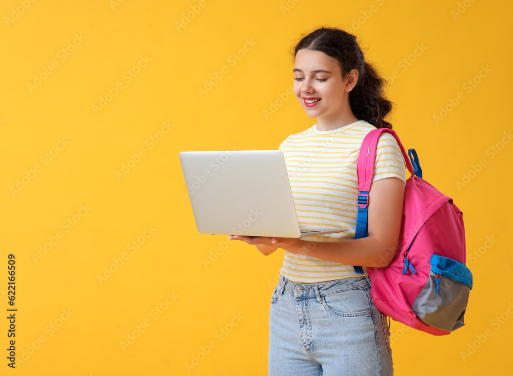 Female student with laptop and backpack on yellow background