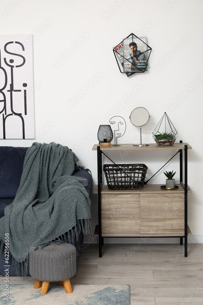 Interior of living room with cozy grey sofa and mirror on shelving unit