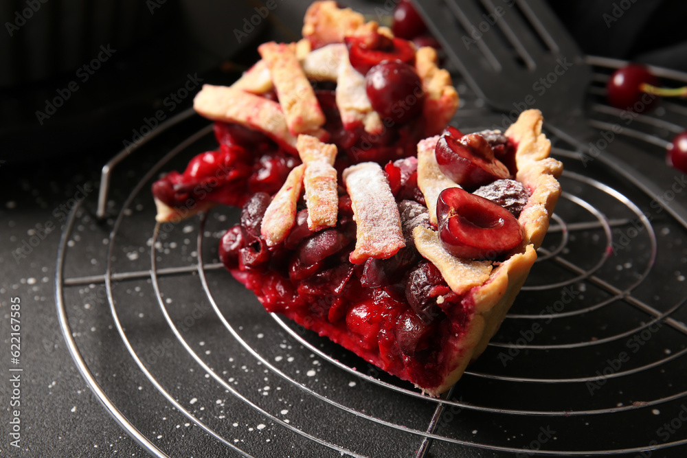 Stand with pieces of tasty cherry pie on black background