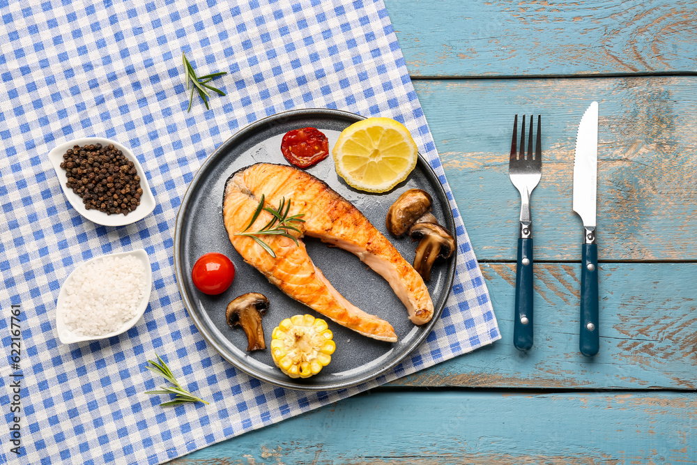 Plate with tasty grilled salmon steak on blue wooden background