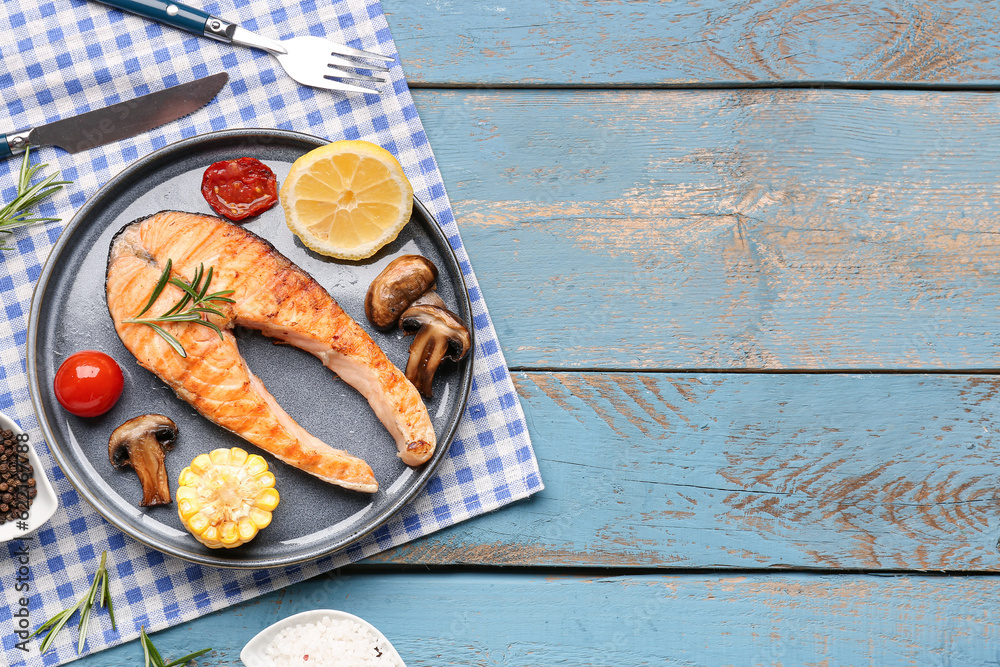 Plate with tasty grilled salmon steak on blue wooden background