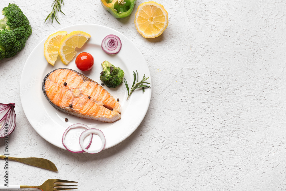 Plate with tasty grilled salmon steak, vegetables and lemon on light background