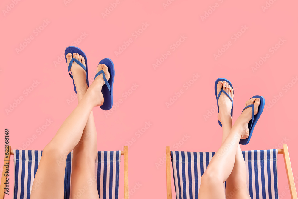 Female legs in flip-flops on pink background