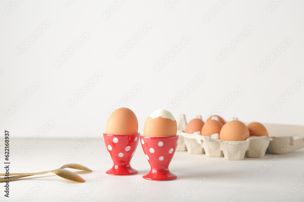 Holders with boiled chicken eggs on white background