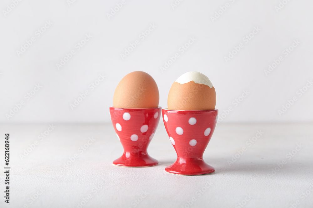 Holders with boiled chicken eggs on white background