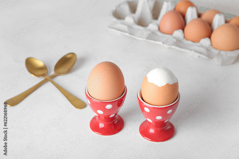 Holders with boiled chicken eggs on white background