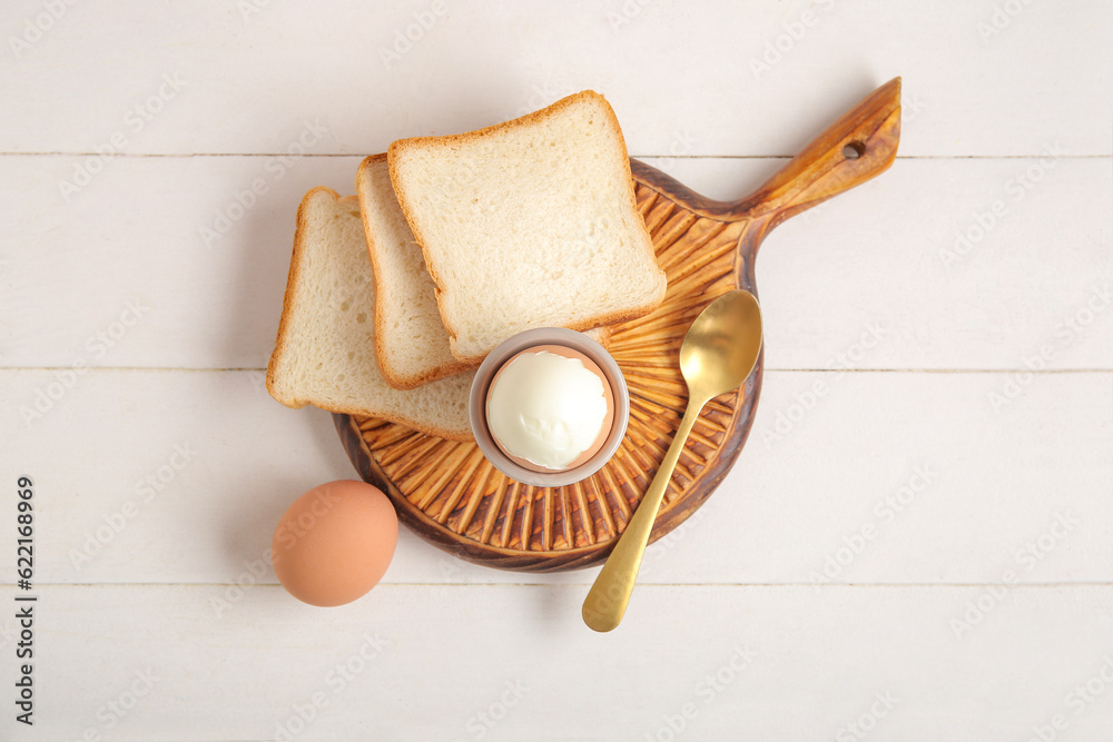 Holder with boiled chicken egg and bread on white wooden background