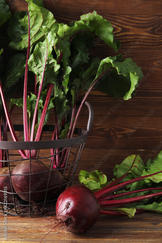 Basket of fresh beets with green leaves on wooden background