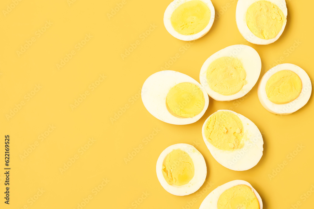 Halves of tasty boiled eggs with slices on yellow background