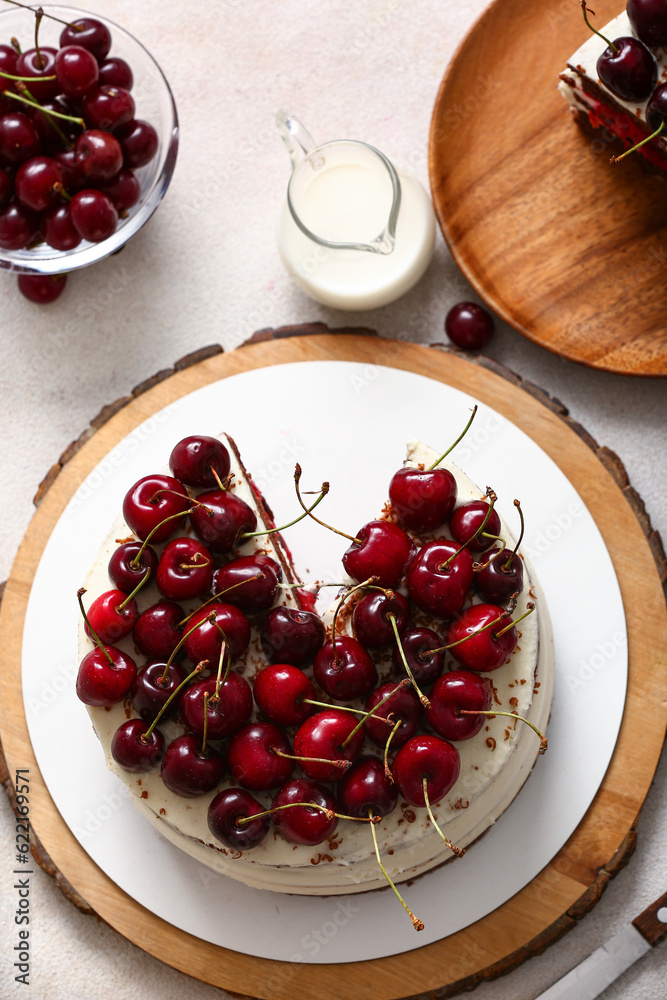 Wooden board with tasty cherry cake on light background