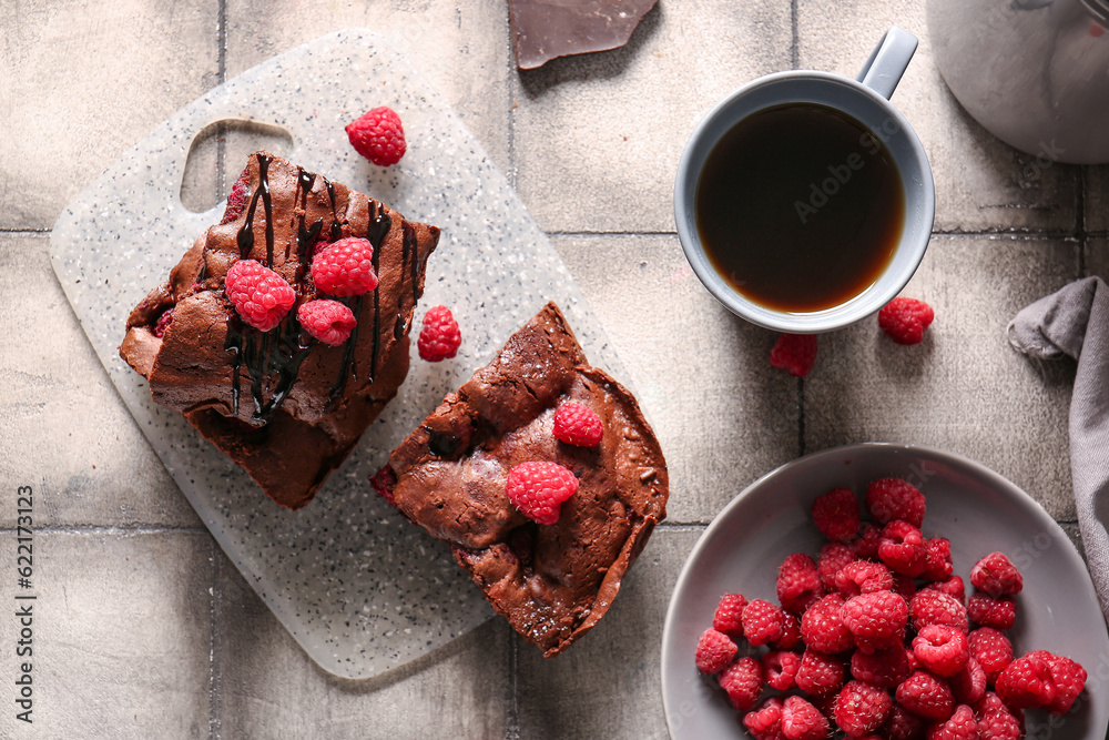 Board with pieces of raspberry chocolate brownie on grey tile table