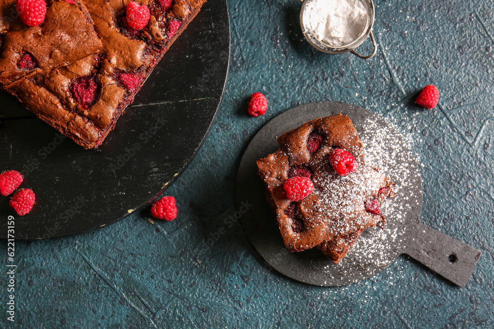 Boards with pieces of raspberry chocolate brownie on dark table