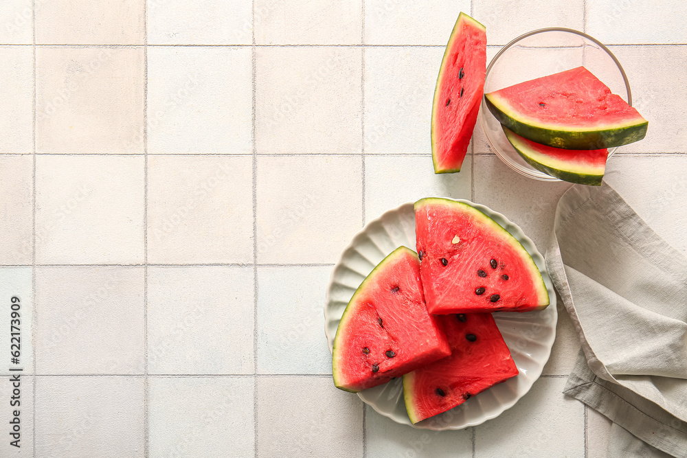 Plate and bowl with pieces of fresh watermelon on white tile table