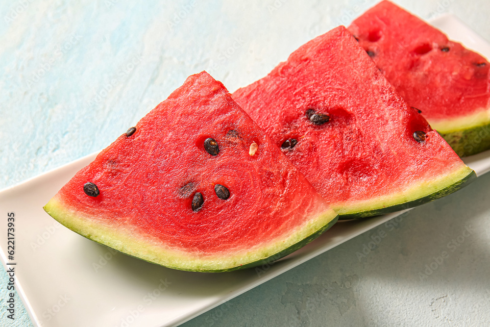 Plate with pieces of fresh watermelon on light blue table