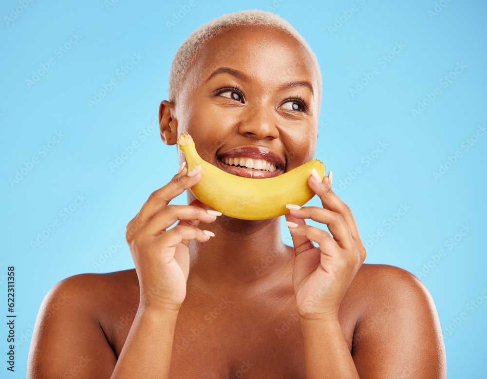 Beauty, smile and banana with a model black woman thinking on a blue background in studio. Skincare,