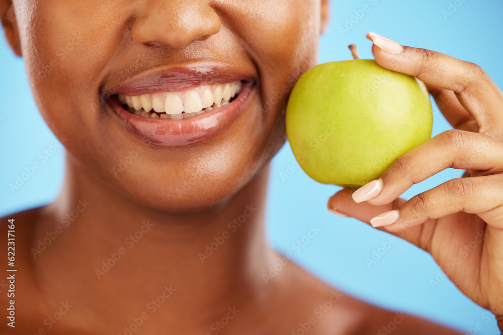 Woman, smile and apple for diet, nutrition or health and wellness against a blue studio background. 