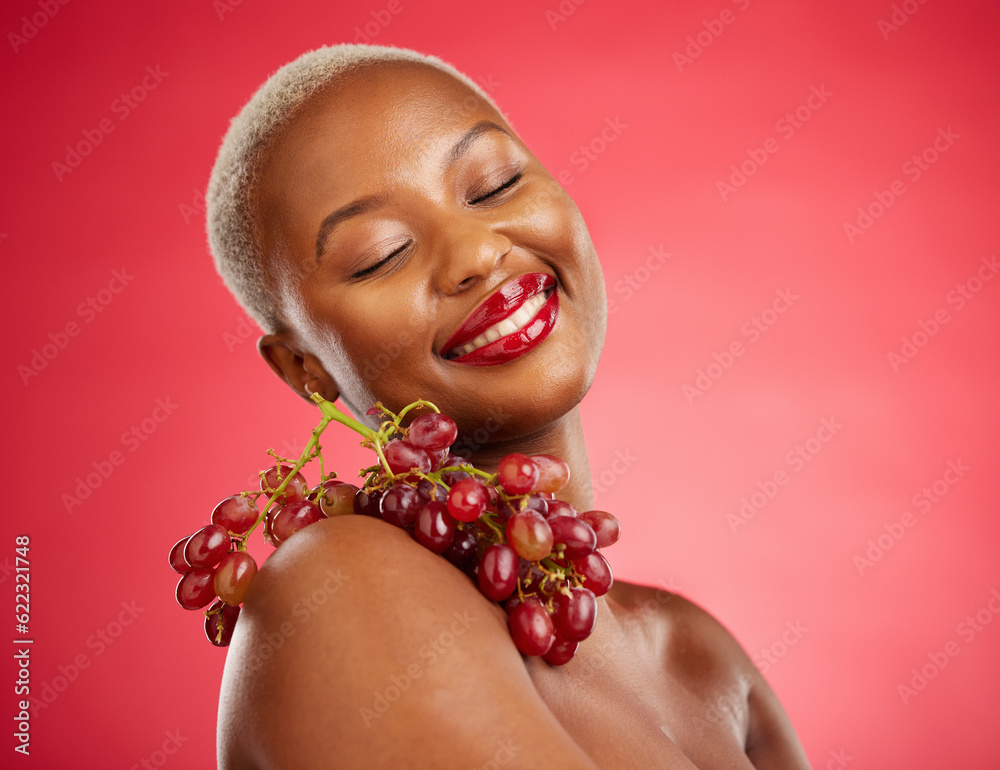 Skincare, smile and grapes with a model black woman in studio on a red background for health or nutr