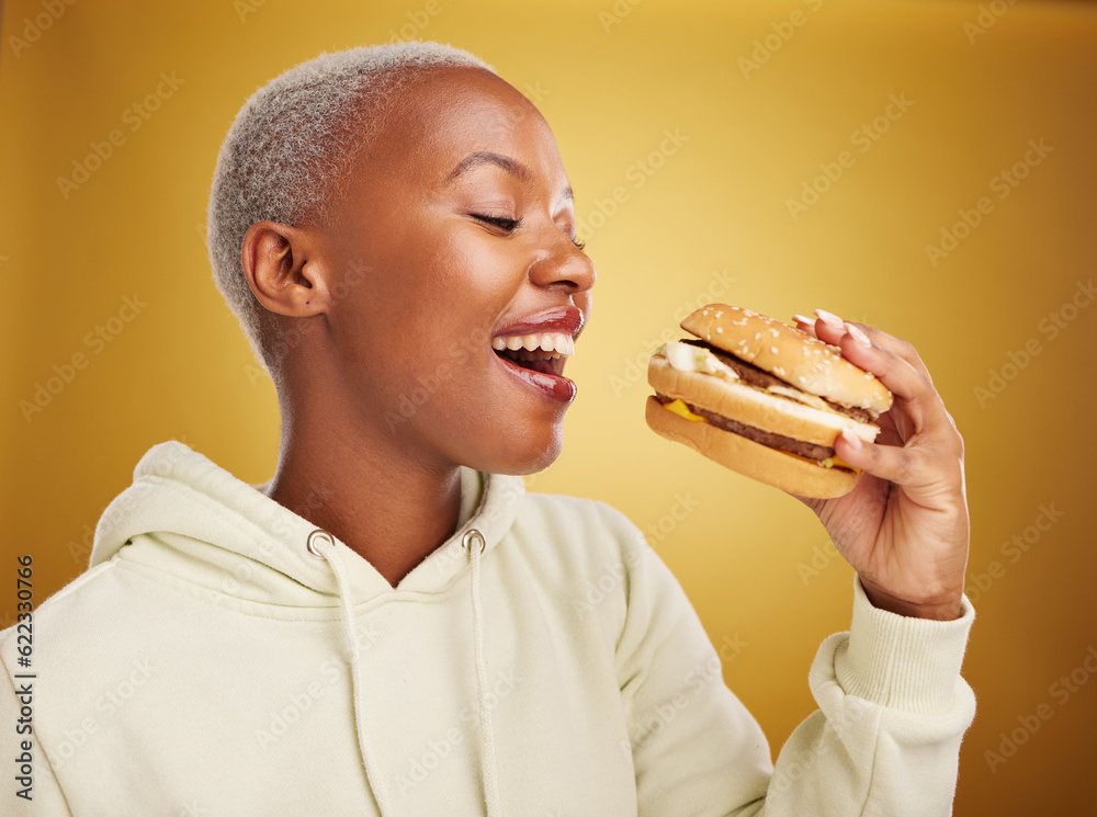 Burger, eating and young woman or student on studio, yellow background for restaurant, lunch and you