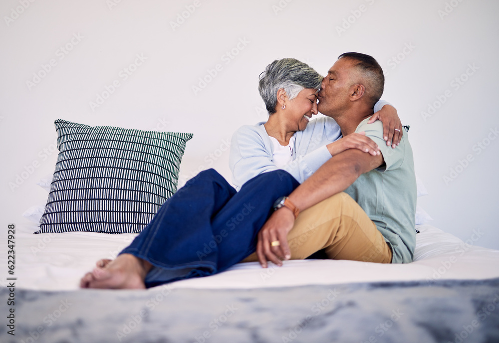 Love, kiss and senior couple on their bed in their home while relaxing, bonding and spending time to